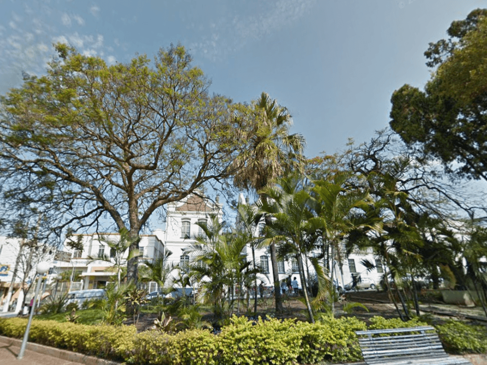 Parque com vegetação exuberante e construções históricas ao fundo, mostrando um dos atrativos de Itu para morar.