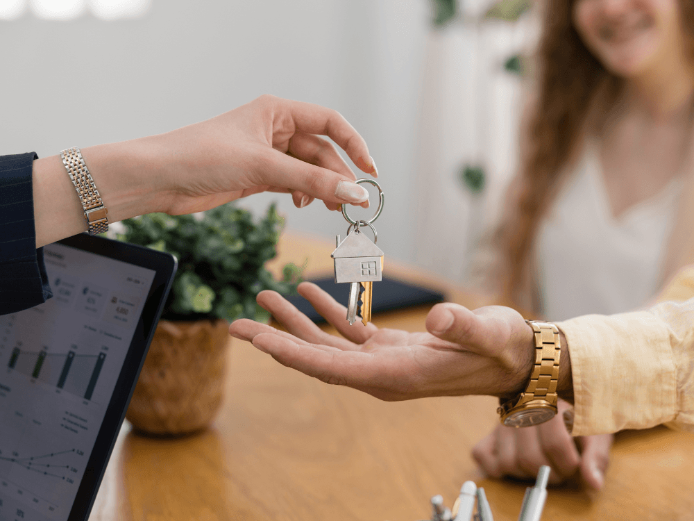 Pessoa entregando chaves de imóvel para cliente durante processo de intermediação imobiliária e conclusão da negociação.