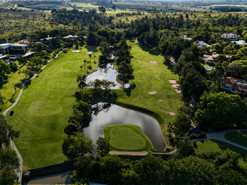 Campo de golfe cercado por árvores, lagos e residências de alto padrão em condomínio residencial sofisticado